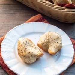 A white plate with a garlic herb parmesan pull apart biscuit.