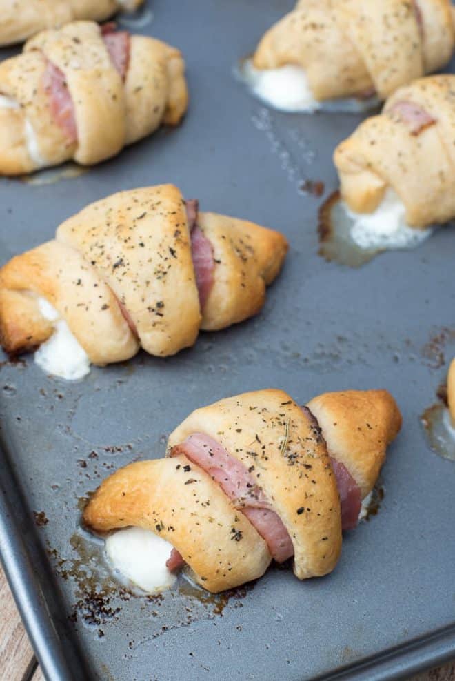 Easy Ham and Cheese Stuffed Crescents on a baking sheet with cheese oozing out.