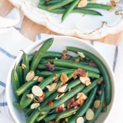 A bowl of green beans topped with sliced almonds.