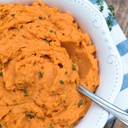 Mashed sweet potatoes in a bowl with a spoon.