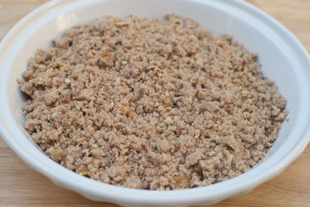 A crumble topping on cake batter in a pie dish.