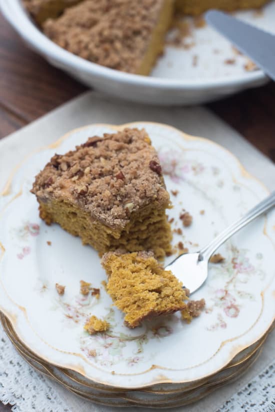 A fork with a bite of Pumpkin Pecan Crumb Cake on a china plate.