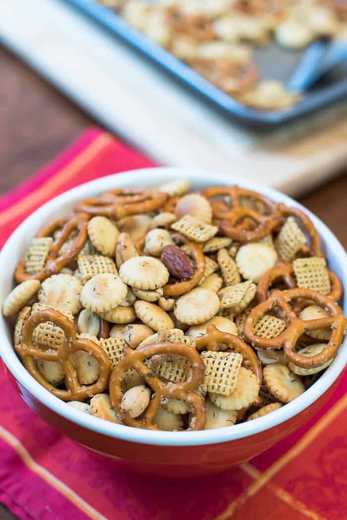 Garlic Dill Snack Mix in a red bowl on a red cloth.