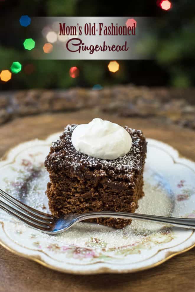 A slice of Old Fashioned Gingerbread on a pretty china plate topped with whipped cream.