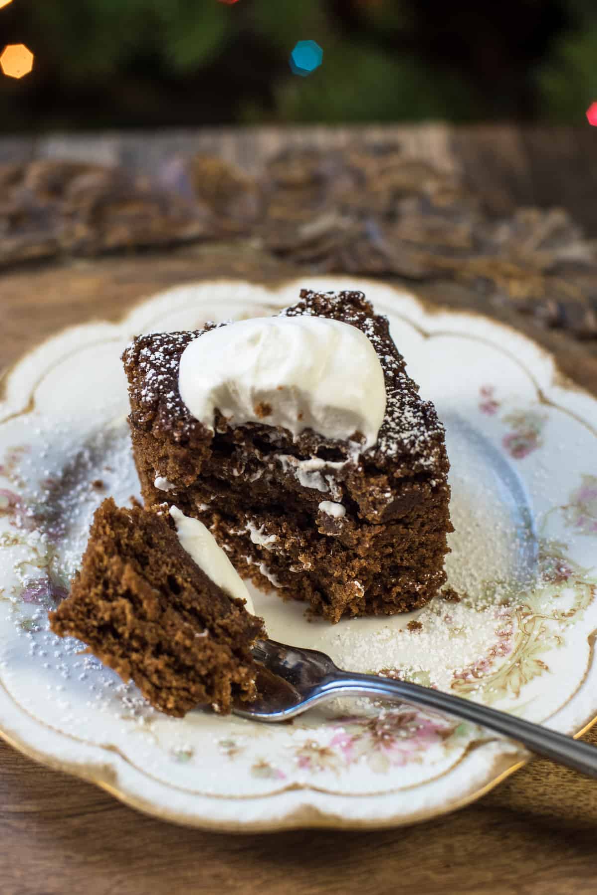 A fork resting on a plate after pulling away a bite of gingerbread cake.