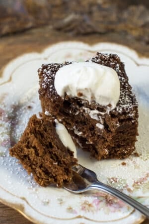 A fork resting on a plate after pulling away a bite of gingerbread cake.