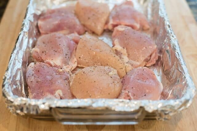 Raw chicken thighs in a foil-lined baking dish.