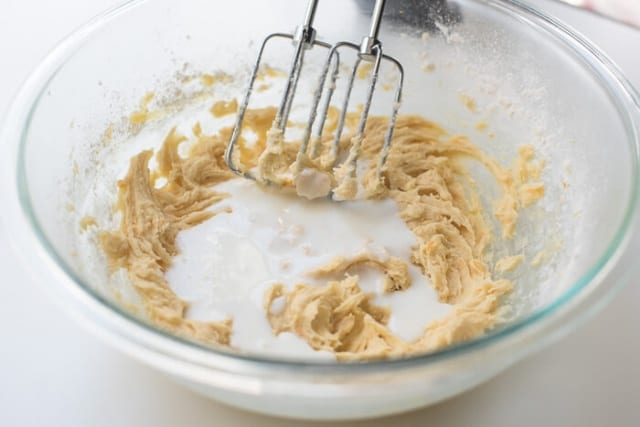 Beaters in a bowl with cake batter and buttermilk.