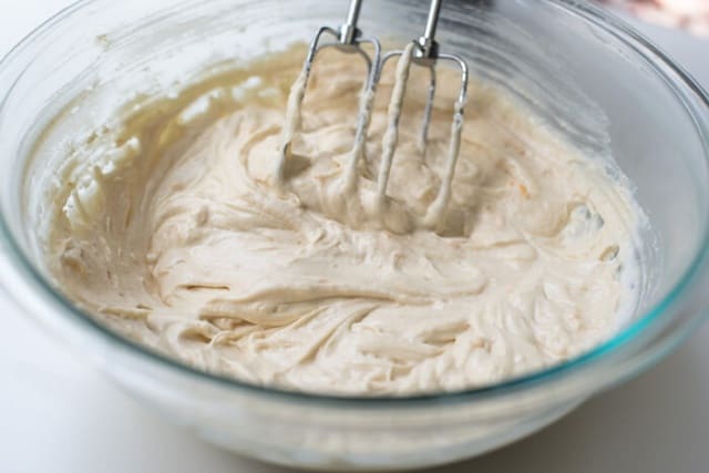 Beaters resting in cake batter in a mixing bowl.