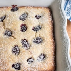 A close up of a blackberry buttermilk snack cake dusted with powdered sugar.