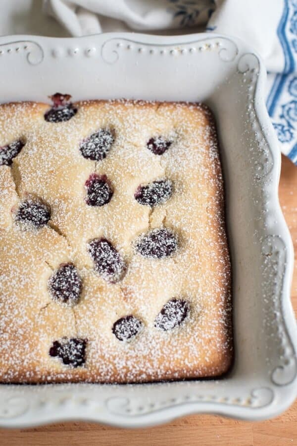 A close up of a blackberry buttermilk snack cake dusted with powdered sugar.