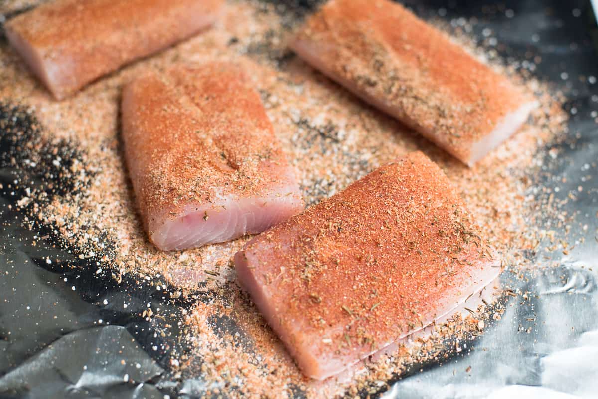 Mahi mahi fillets on foil topped with Cajun spice mix.