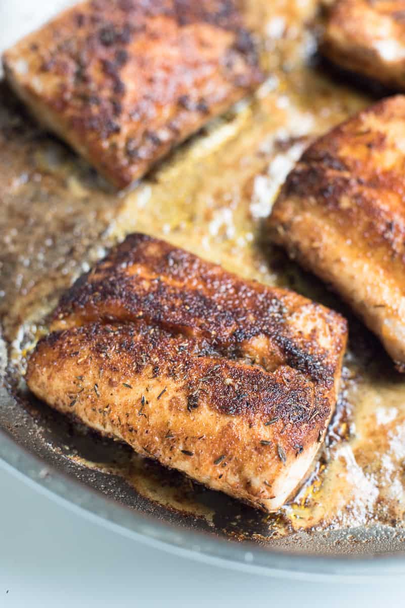 Seasoned fish fillets cooking in a skillet.