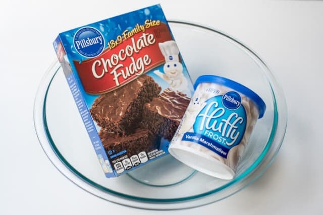 A box of Pillsbury Chocolate Fudge Brownie Mix and cannister of Pillsbury Fluffy Frost Vanilla Marshmallow.