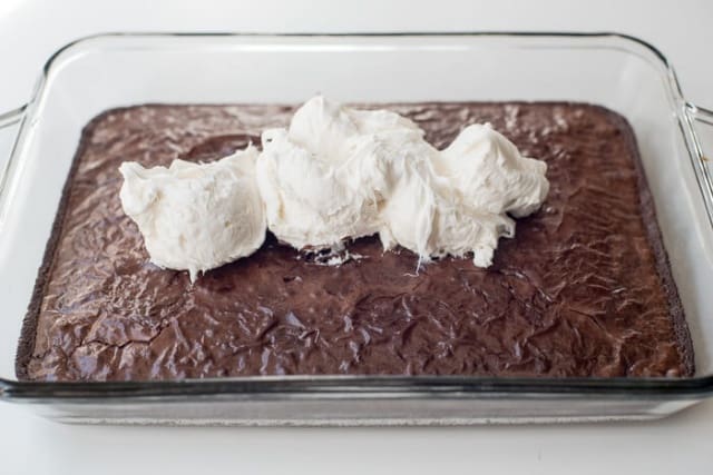 Big dollops of marshmallow frosting on top of brownies in a baking dish.