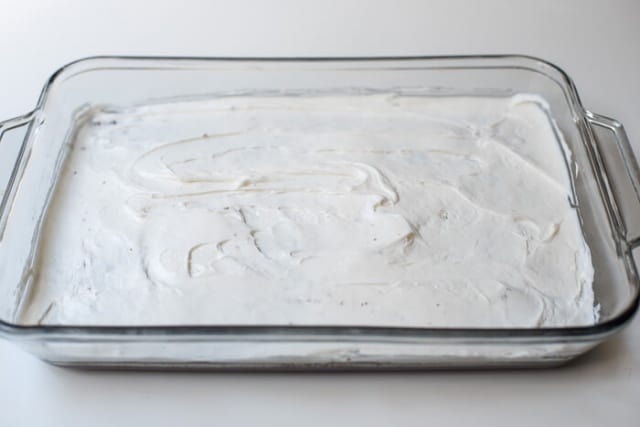 Marshmallow frosting spread out over a brownie layer in a baking dish.