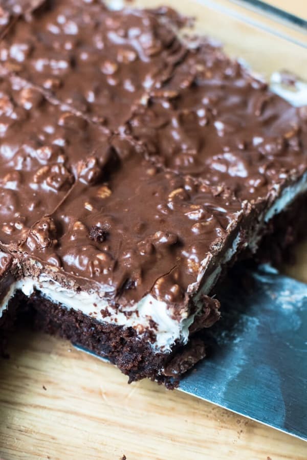 A spatula lifts a Brownie Marshmallow Crunch Bars from a baking dish.