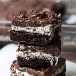 Brownie Marshmallow Crunch Brownies stacked on a white plate.