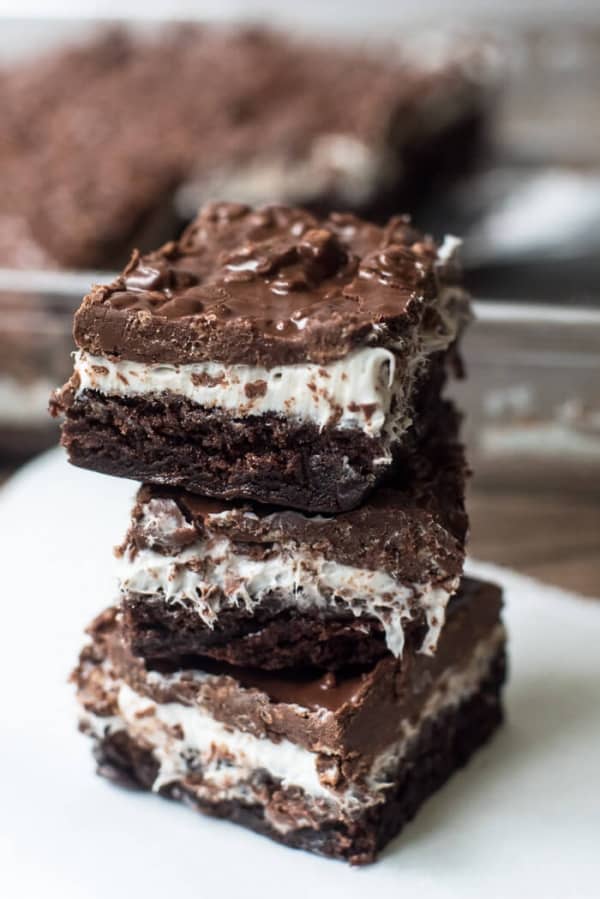 A stack of Brownie Marshmallow Crunch Bars on parchment paper.