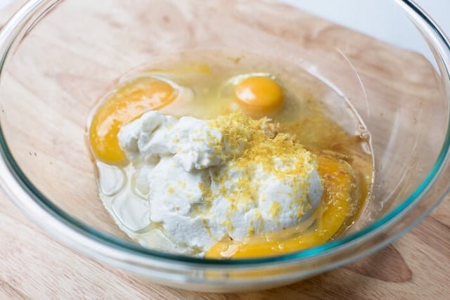 Greek yogurt, sugar, eggs, oil, vanilla, and lemon in a mixing bowl.