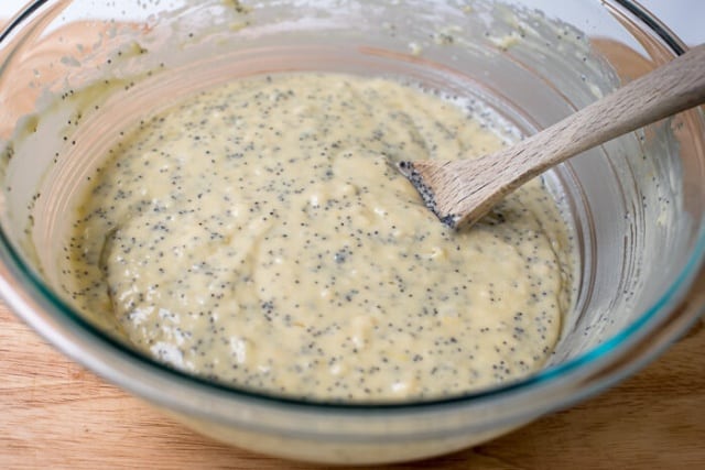 Lemon Yogurt Poppy Seed Bread batter in a mixing bowl with a wooden spoon.