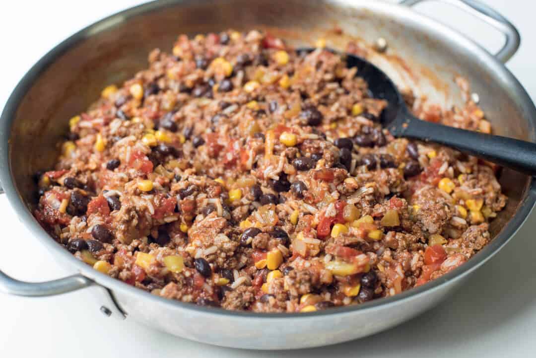 Mexican bell pepper filling in a skillet with a spoon.