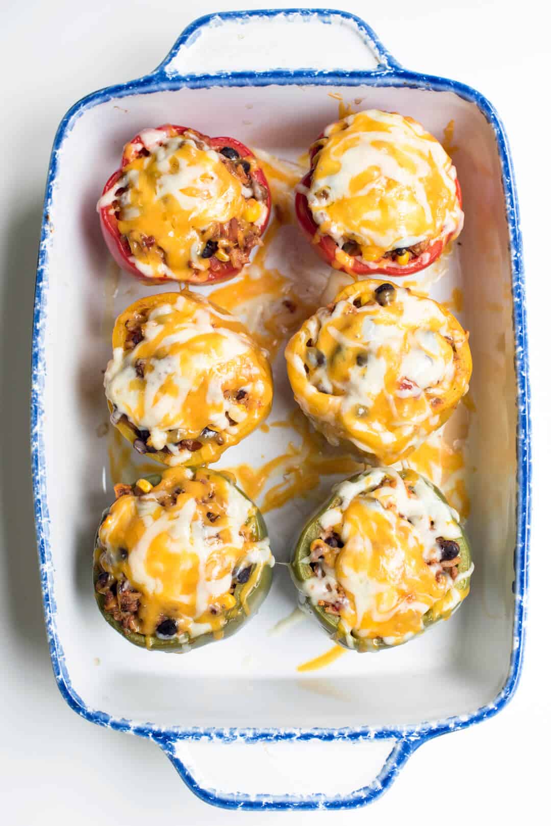 Colorful bell peppers stuffed with a meat filling and topped with melted cheese shot from over the top.