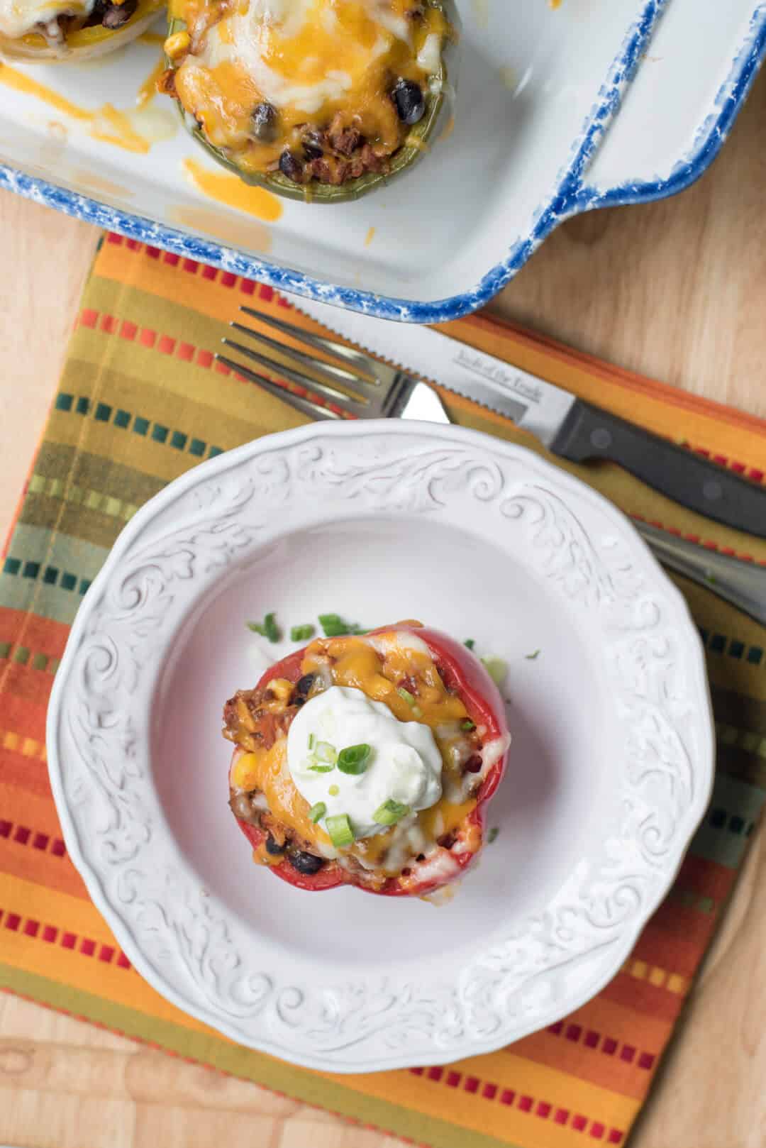 A Mexican Stuffed Bell Pepper on a white plate on a colorful cloth shot from over the top.