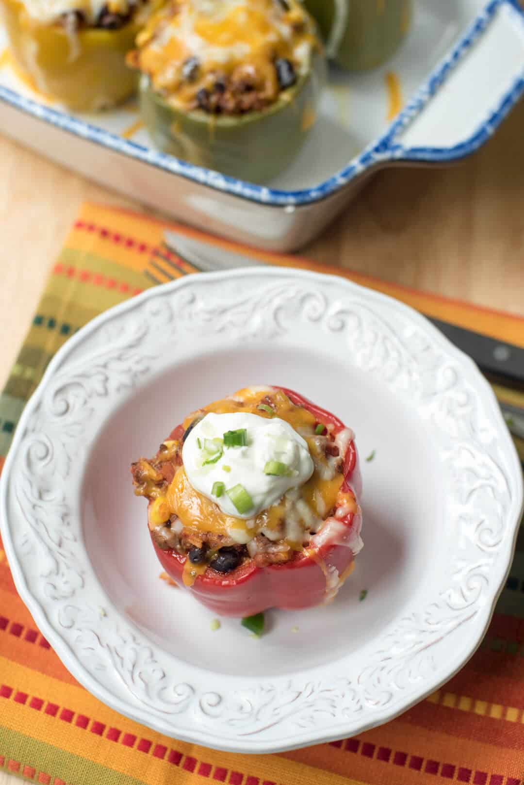 A Mexican Stuffed Pepper topped with sour cream in a white bowl.