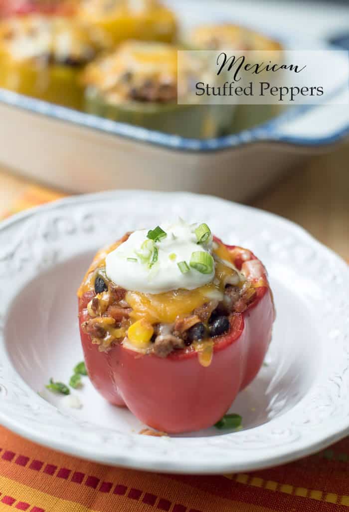 A stuffed red bell pepper topped with sour cream on a plate with overlay text.