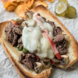 A drip beef sandwich with melted provolone on parchment paper.