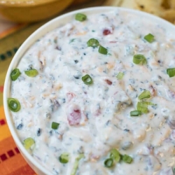 A bowl of southwestern ranch dip topped with sliced green onions.