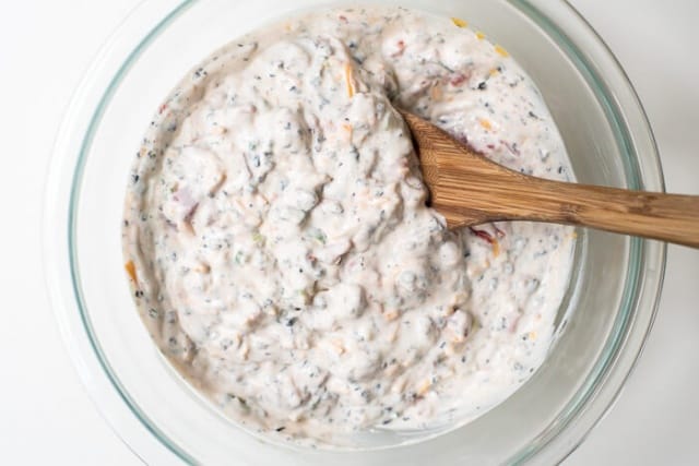 Dip ingredients mixed together in a bowl with a wooden spoon.