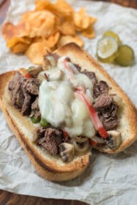 Shredded drip beef on a toasted sandwich roll with peppers, onions, and melted cheese.