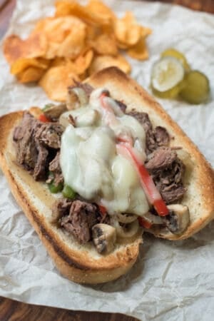 Shredded drip beef on a toasted sandwich roll with peppers, onions, and melted cheese.