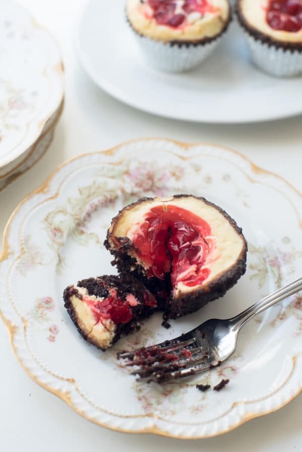 A fork resting on a pretty china plate with a Cherry Cheesecake Brownie Cupcake.