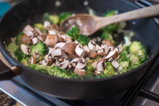 Broccoli and mushrooms cooking in a skillet.