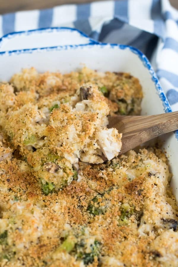 A spoon scoops chicken casserole from a baking dish.