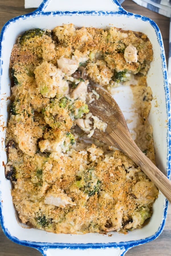 A wooden spoon rests in a Creamy Chicken Broccoli and Rice Casserole.