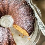 A bundt caked dusted with powdered sugar with one piece missing.