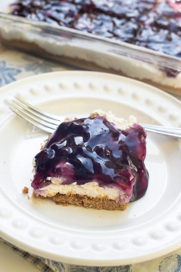 A slice of cheesecake with blueberry topping on a plate.