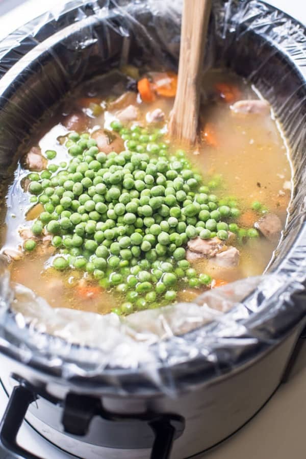Frozen peas in a low cooker with broth and other ingredients.