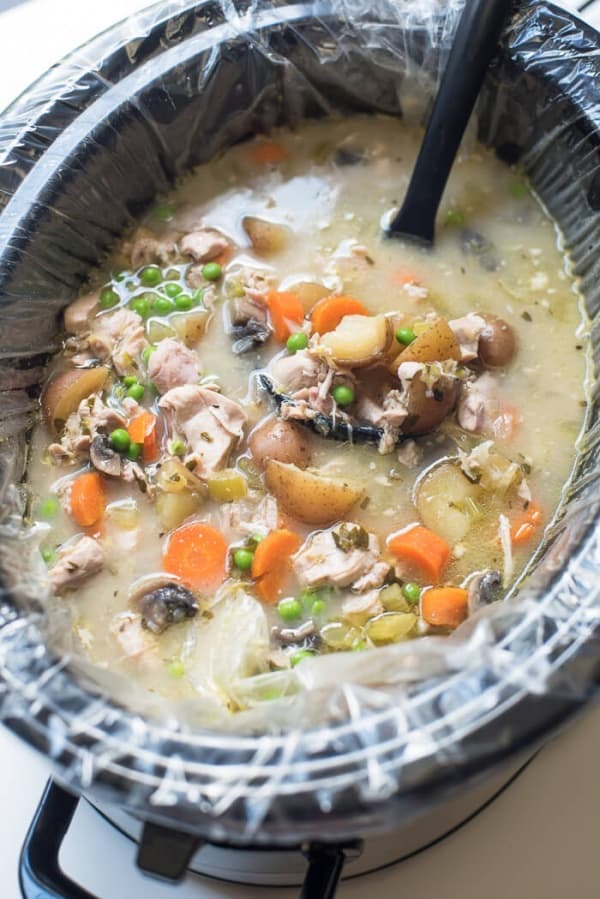 Slow Cooker Chicken and Spring Vegetable Stew in a slow cooker with a spoon.