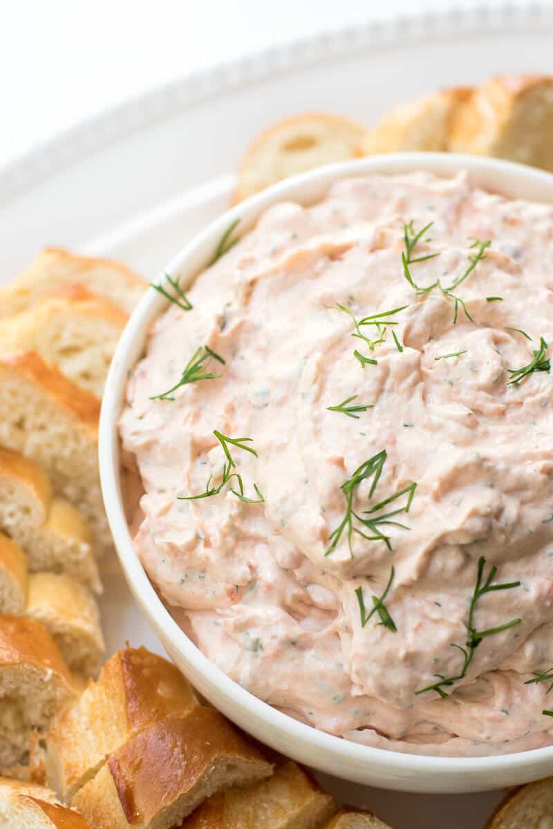 Smoked Salmon Dip in a white serving bowl with sliced baguette placed around it.