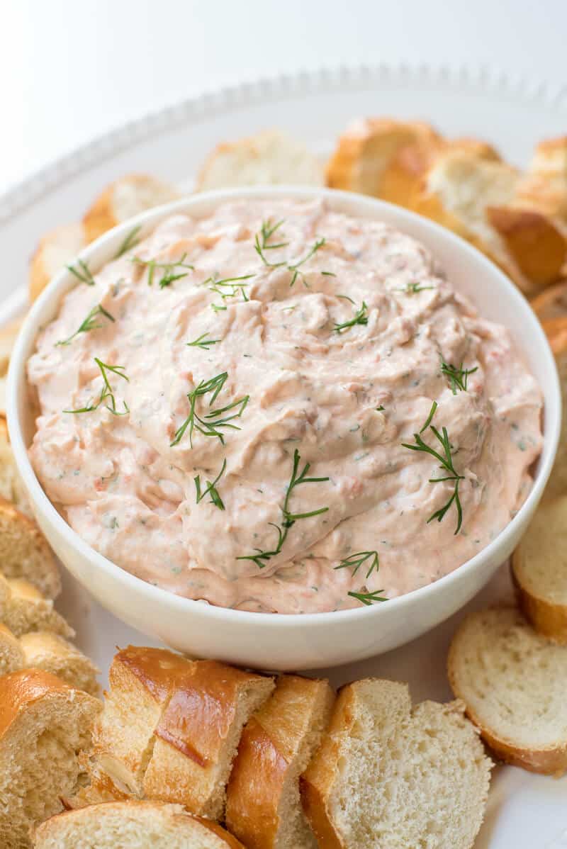 Smoked Salmon Dip in a white bowl surrounded by sliced bread.