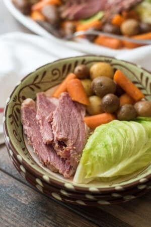 Sliced corned beef with cabbage, potatoes, and carrots in a bowl.