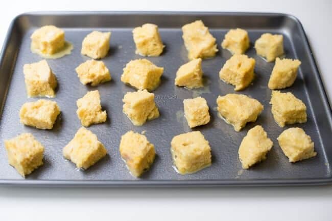 The egg soaked bread cubes on a baking sheet.