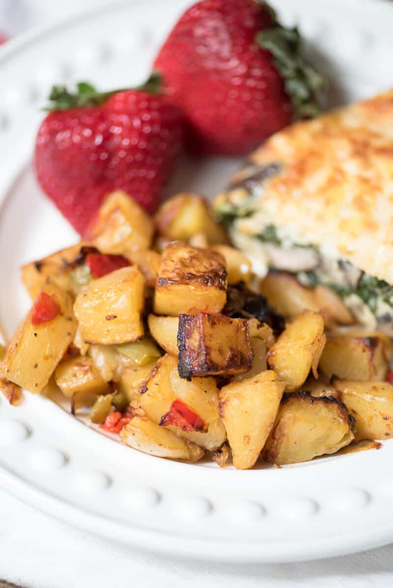 Oven Roasted Breakfast Potatoes on a white plate with strawberries