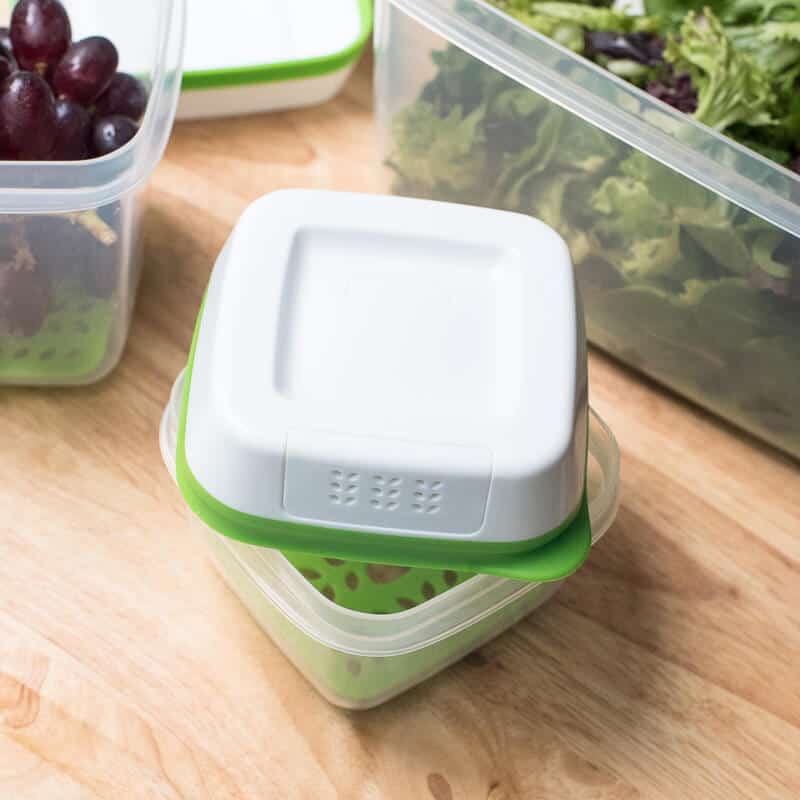 A Rubbermaid FreshWorks Produce Saver on a kitchen counter with lettuce greens and grapes.