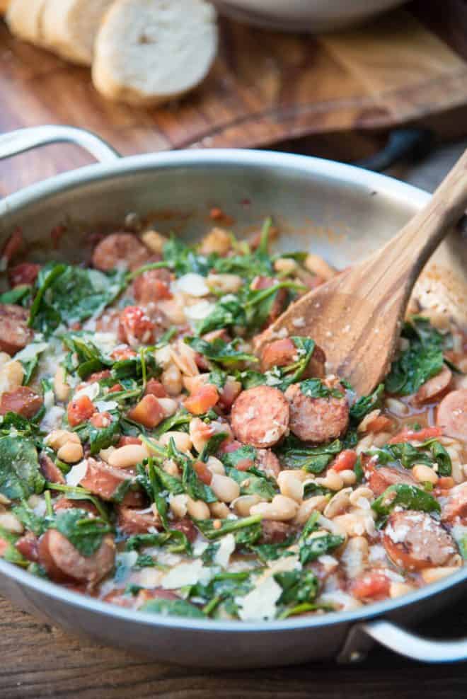 Skillet Sausage and White Beans with Spinach in a stainless steel skillet.